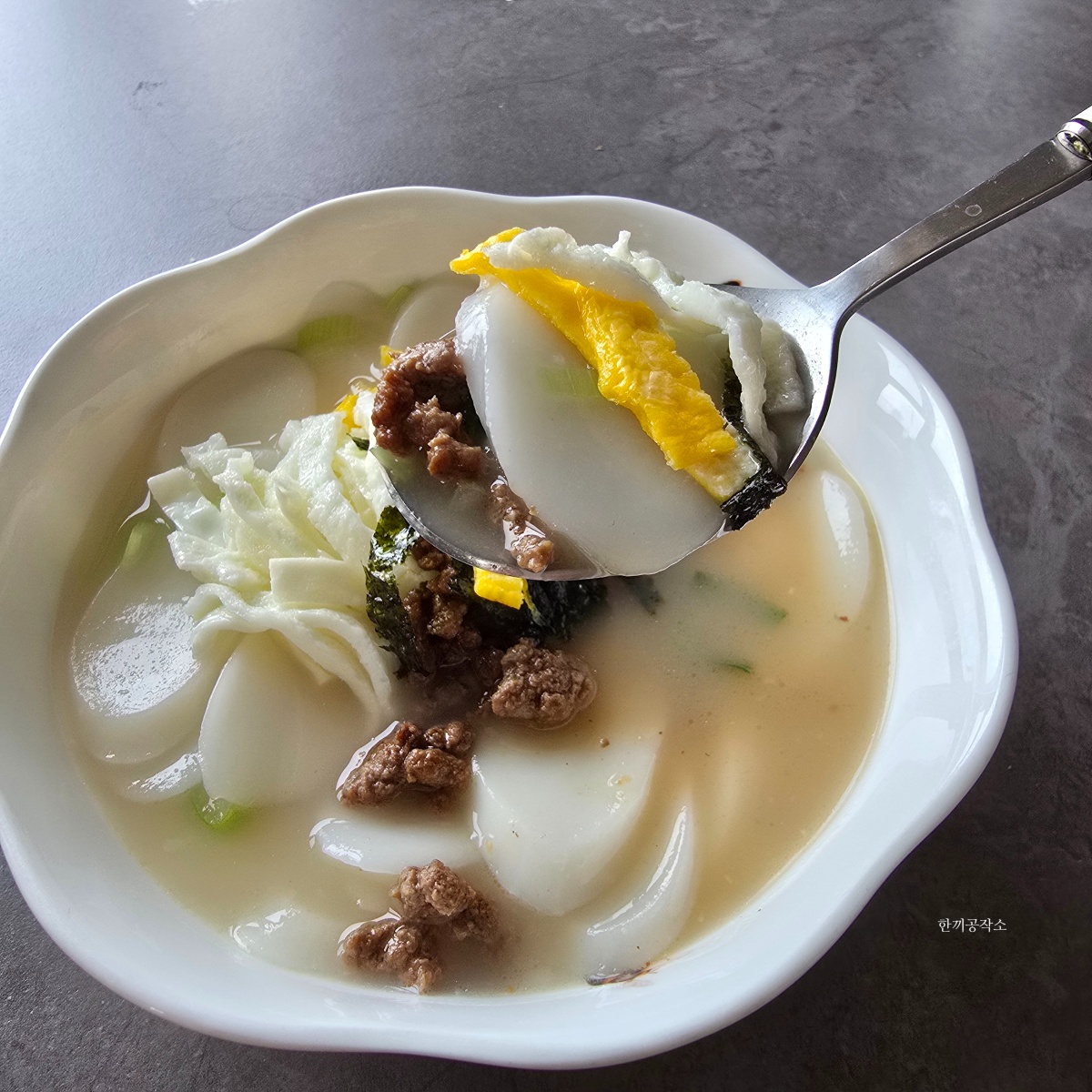 부드러운 떡과 고명을 함께 떠먹는 떡국 한 숟가락